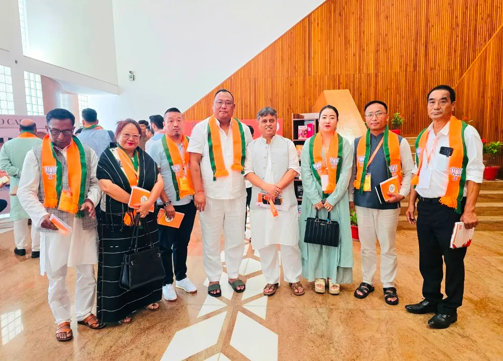 Benjamin Yepthomi standing with seven other BJP Nagaland leaders wearing party scarves at a national-level party meeting venue.