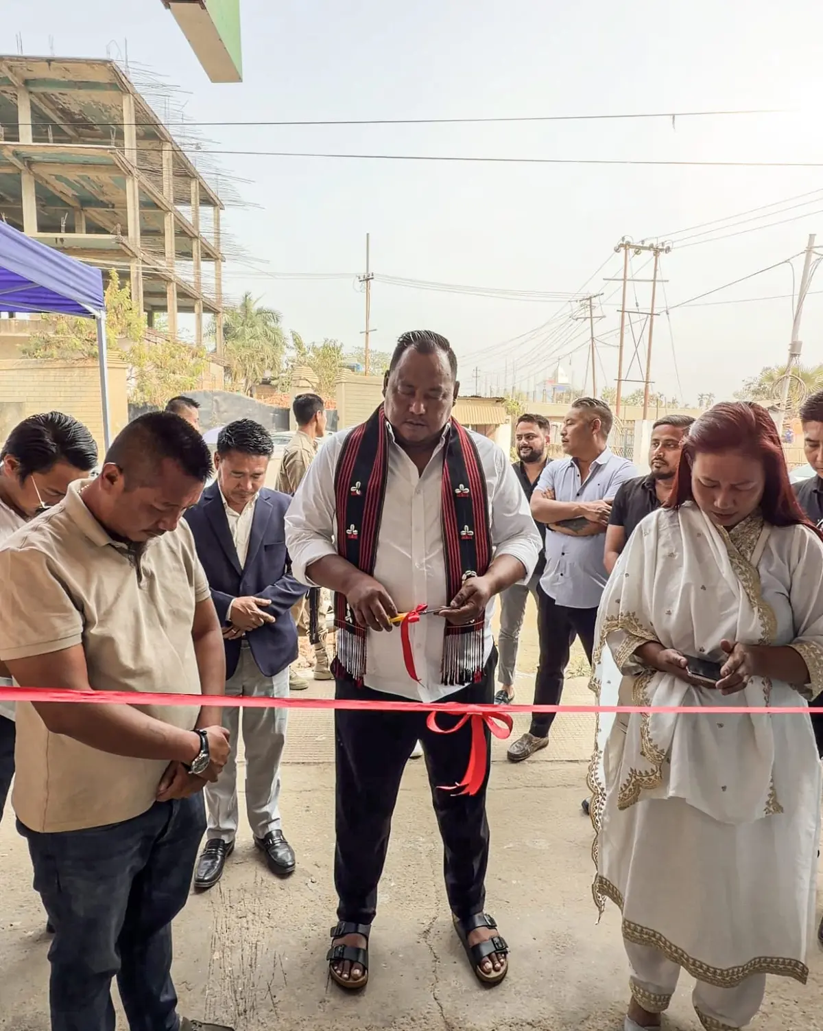 Benjamin Yepthomi cutting a red ribbon to inaugurate the BJYM Nagaland president's office, with party workers standing on either side.